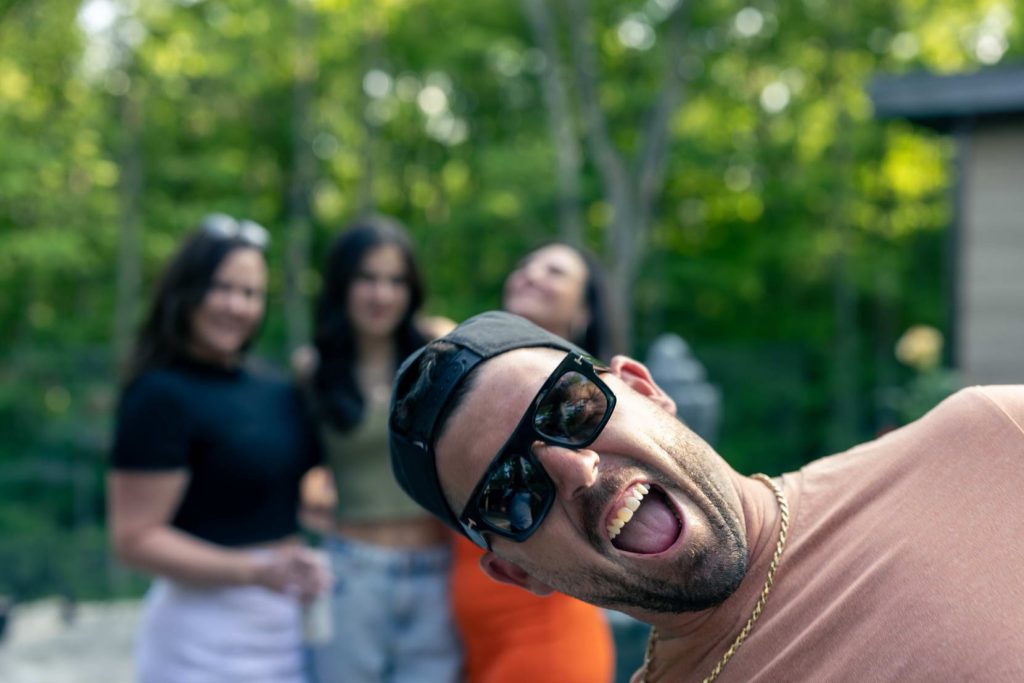 Smiling man in sunglasses posing playfully at an outdoor event, captured candidly by Yuri York Photography in Ottawa.