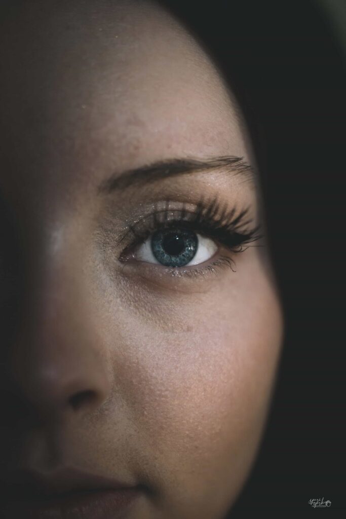 Close-up artistic portrait of a woman’s eye in dramatic lighting, showcasing detail and emotion.