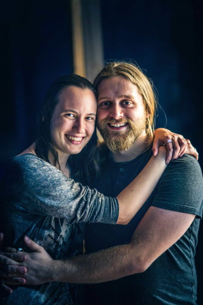 Smiling couple embracing indoors, captured in warm natural light