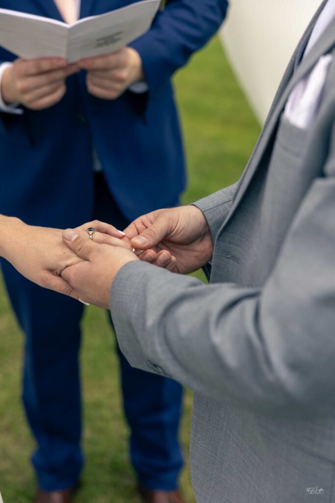 Close-up of hands during a wedding ceremony, capturing the ring exchange moment.